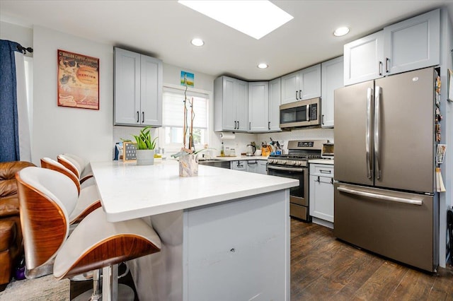146 First St, Yonkers, NY 10704 - kitchen with appliances with stainless steel finishes, a peninsula, a breakfast bar area, dark wood-style flooring, and light countertops
