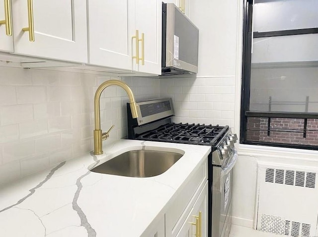 150-29 72nd Rd Unit 5E, Kew Garden Hills, NY 11367 - kitchen with stainless steel range with gas stovetop, white cabinetry, a sink, light stone countertops, and backsplash