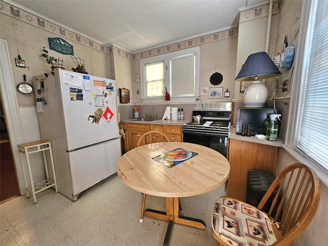 173-12 93rd Ave, Jamaica, NY 11433 - kitchen featuring freestanding refrigerator, range, plenty of natural light, light countertops, and wallpapered walls
