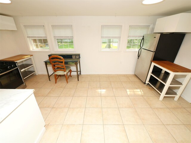 35 Junard Blvd, Port Jefferson Station, NY 11776 - kitchen featuring stainless steel range with gas stovetop, freestanding refrigerator, white cabinets, premium range hood, and light tile patterned flooring