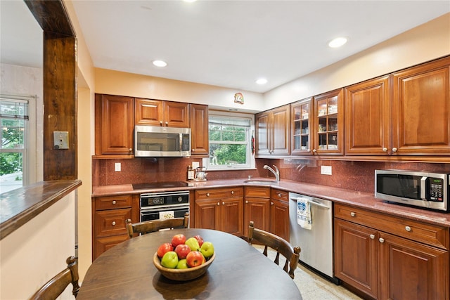 82 Cherry Ln, Lynbrook, NY 11563 - kitchen featuring black appliances, brown cabinets, decorative backsplash, glass insert cabinets, and recessed lighting