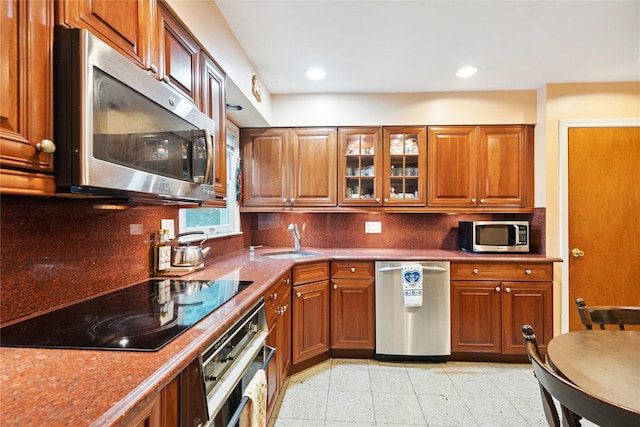 82 Cherry Ln, Lynbrook, NY 11563 - kitchen with appliances with stainless steel finishes, backsplash, brown cabinets, recessed lighting, and glass insert cabinets