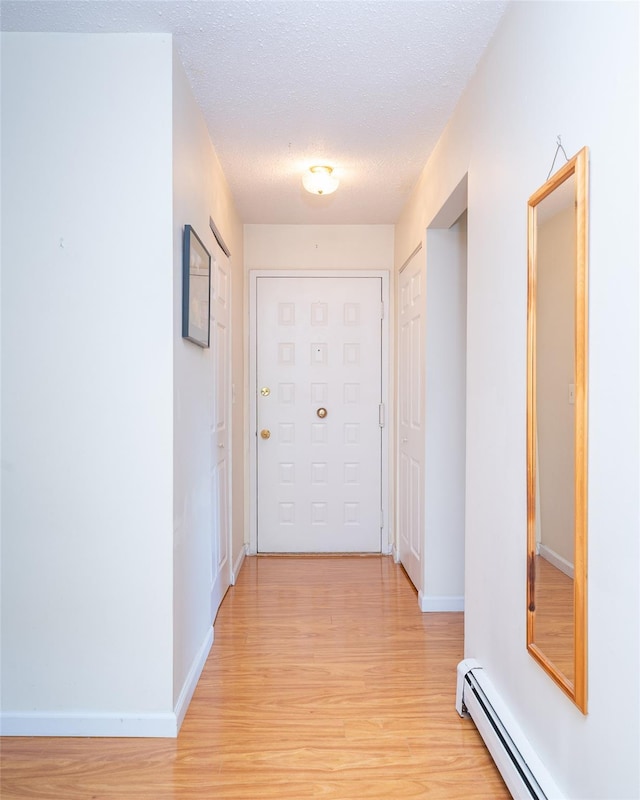 7-05 Briarcliff Dr S, Ossining, NY 10562 - hallway with a baseboard radiator, light wood-style flooring, a textured ceiling, and baseboards