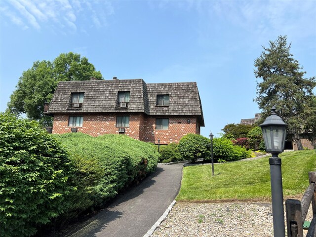 7-05 Briarcliff Dr S, Ossining, NY 10562 - view of home's exterior with brick siding, mansard roof, and a lawn