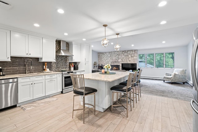 183 Iceland Dr, South Huntington, NY 11746 - kitchen featuring wall chimney range hood, a sink, appliances with stainless steel finishes, open floor plan, and a baseboard radiator