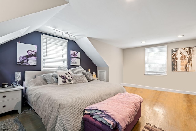183 Iceland Dr, South Huntington, NY 11746 - bedroom with multiple windows, wood finished floors, vaulted ceiling, baseboards, and rail lighting