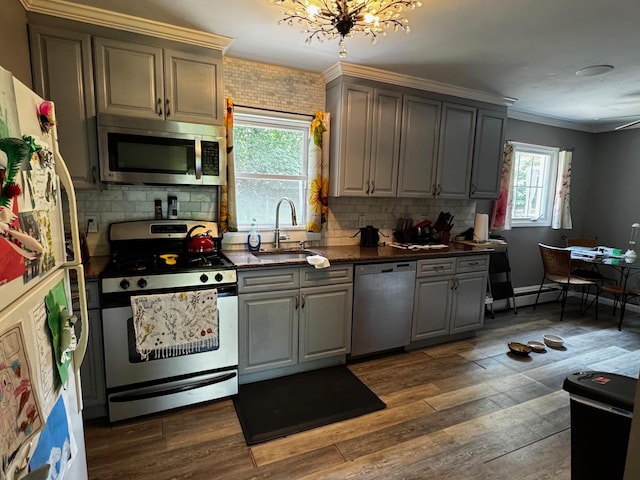 2 Paulding St, Huntington, NY 11743 - kitchen featuring appliances with stainless steel finishes, gray cabinetry, a sink, crown molding, and decorative backsplash