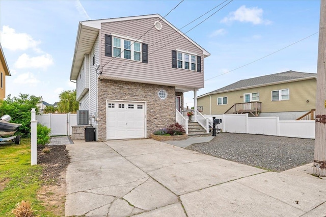 845 Atlantic St, Lindenhurst, NY 11757 - view of front facade with stone siding, a garage, a gate, driveway, and central AC