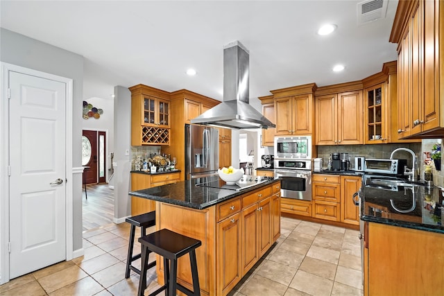 3856 Marcy St, Mohegan Lake, NY 10547 - kitchen featuring stainless steel appliances, island range hood, backsplash, brown cabinetry, and dark stone countertops