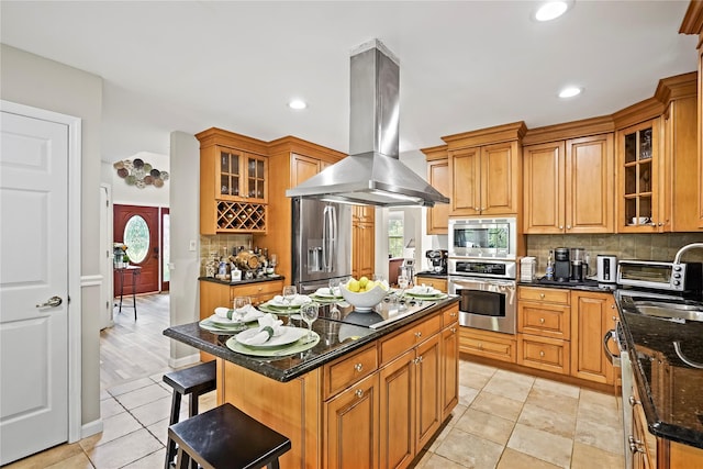 3856 Marcy St, Mohegan Lake, NY 10547 - kitchen featuring appliances with stainless steel finishes, island exhaust hood, decorative backsplash, dark stone counters, and a kitchen island