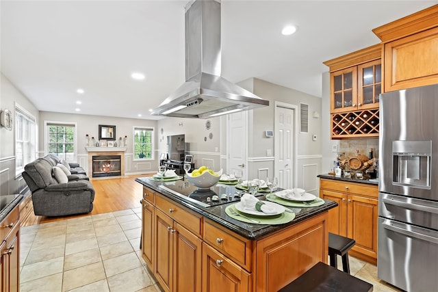 3856 Marcy St, Mohegan Lake, NY 10547 - kitchen featuring stainless steel refrigerator with ice dispenser, island range hood, a kitchen island, light tile patterned flooring, and a glass covered fireplace