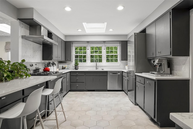 71 Baraud Rd S, Scarsdale, NY 10583 - kitchen with appliances with stainless steel finishes, wall chimney range hood, a skylight, tasteful backsplash, and recessed lighting