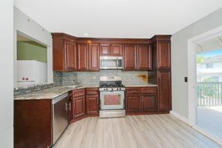 293 Wingham St, Staten Island, NY 10303 - kitchen with appliances with stainless steel finishes, decorative backsplash, light wood finished floors, light countertops, and a sink