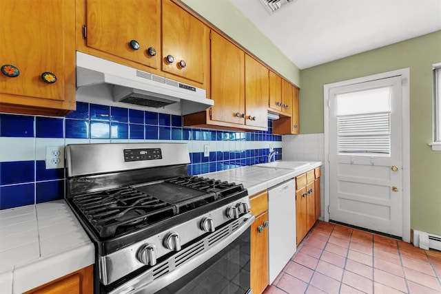 102 Maple St, Croton-On-Hudson, NY 10520 - kitchen featuring stainless steel gas stove, under cabinet range hood, tile counters, white dishwasher, and tasteful backsplash