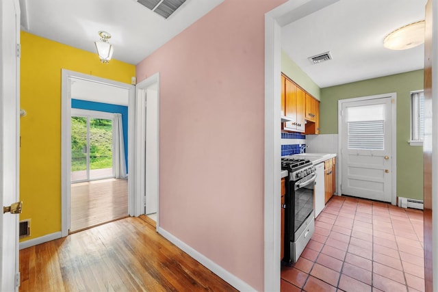 102 Maple St, Croton-On-Hudson, NY 10520 - kitchen featuring stainless steel gas stove, a baseboard radiator, light countertops, under cabinet range hood, and backsplash