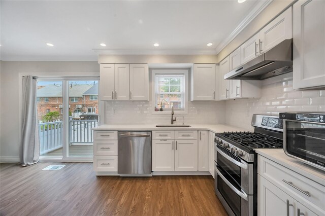 239-53 66th Ave, Little Neck, NY 11362 - kitchen with stainless steel appliances, under cabinet range hood, a sink, ornamental molding, and wood finished floors