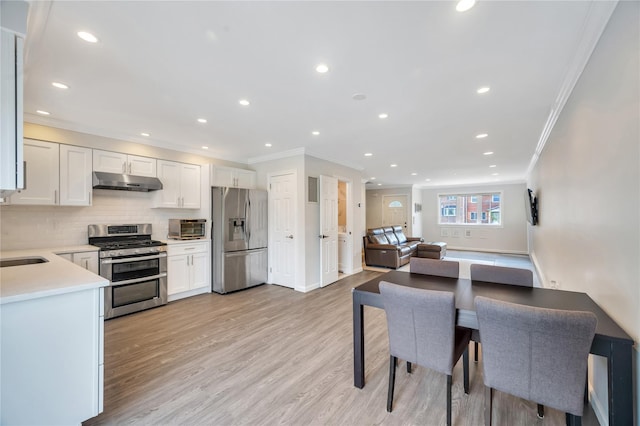 239-53 66th Ave, Little Neck, NY 11362 - kitchen featuring appliances with stainless steel finishes, under cabinet range hood, crown molding, light countertops, and tasteful backsplash