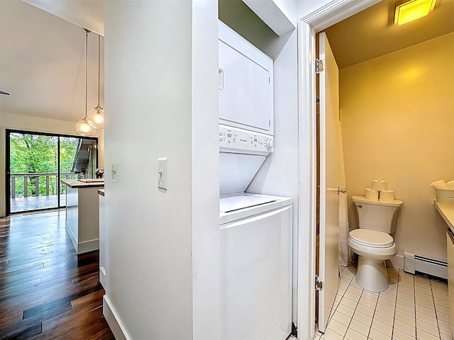 24 Lakeview Ter, Monticello, NY 12701 - laundry room featuring stacked washing machine and dryer, a baseboard heating unit, and wood finished floors