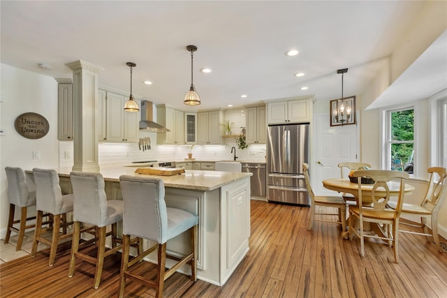 41 Indian Hill Rd, Brewster, NY 10509 - kitchen featuring stainless steel appliances, wall chimney exhaust hood, a peninsula, decorative backsplash, and light wood-type flooring
