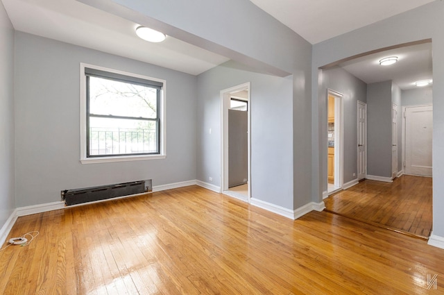 22-20 76th St Unit C3, East Elmhurst, NY 11370 - unfurnished room featuring a baseboard radiator, light wood-style flooring, arched walkways, and baseboards