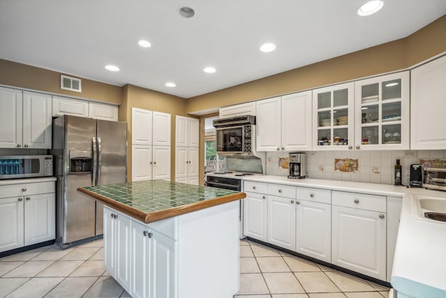55 Maple Run Dr, Jericho, NY 11753 - kitchen featuring stainless steel refrigerator with ice dispenser, white cabinetry, a kitchen island, light tile patterned floors, and recessed lighting