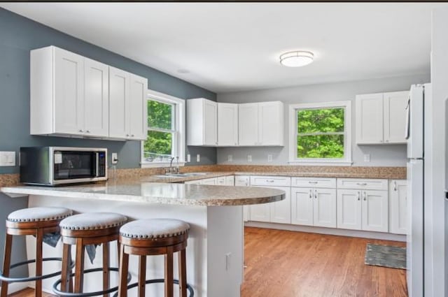 484 N Magee St, Southampton, NY 11968 - kitchen featuring stainless steel microwave, a sink, a peninsula, and white cabinets