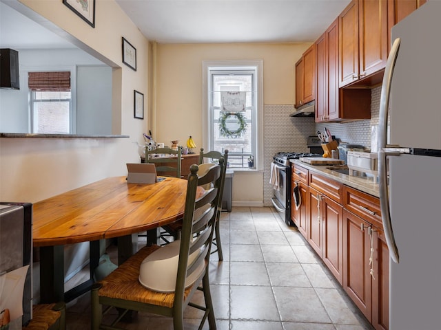 1840 21st Dr, Astoria, NY 11105 - kitchen featuring freestanding refrigerator, gas stove, under cabinet range hood, backsplash, and light tile patterned floors