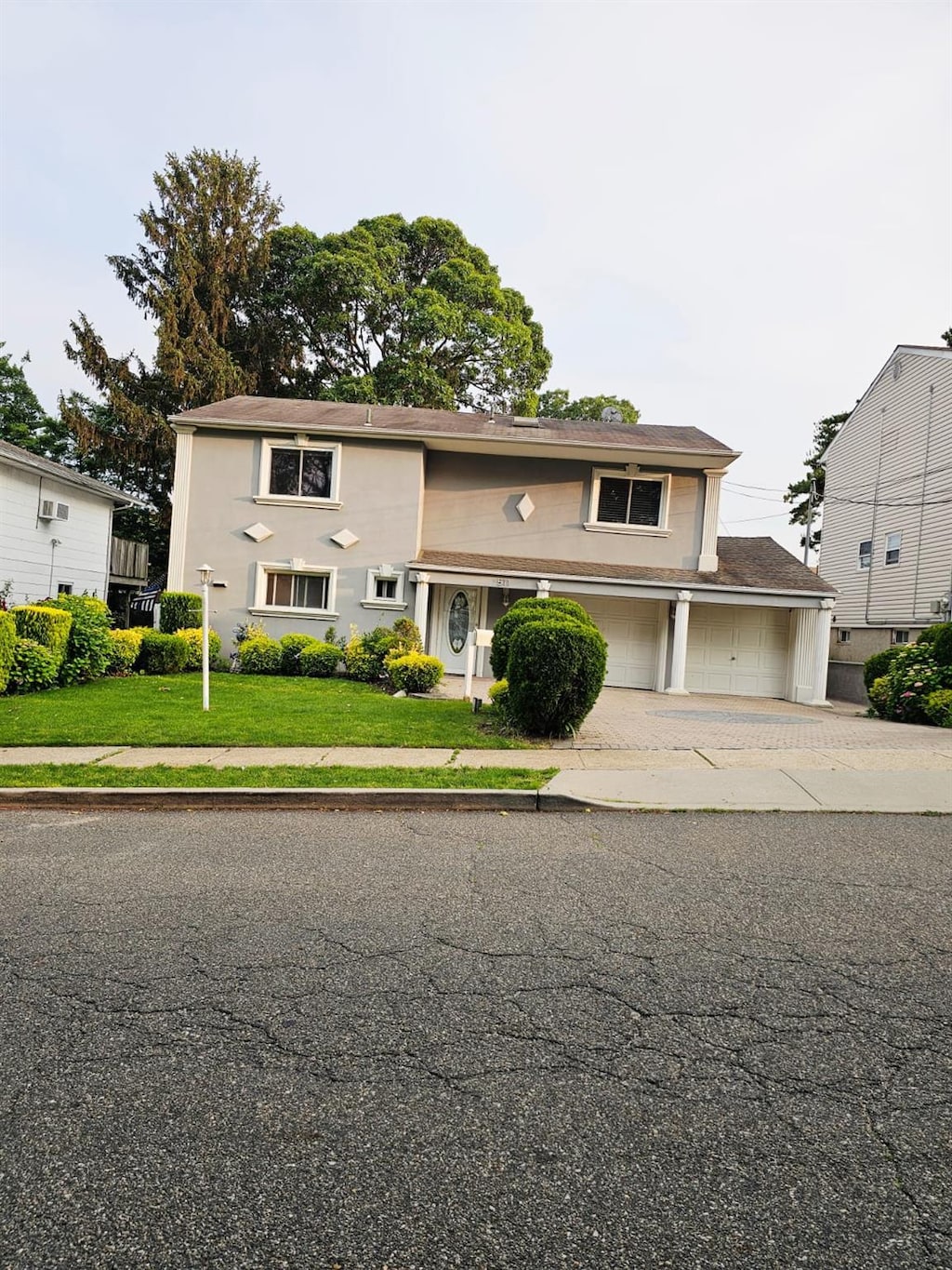 511 Chesman St, Hempstead, NY 11552 - traditional-style home featuring driveway, a front lawn, and a garage