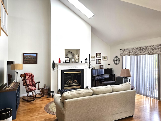 107 Scenic Lake Dr Unit 107, Riverhead, NY 11901 - living area with high vaulted ceiling, light wood finished floors, a glass covered fireplace, and a skylight