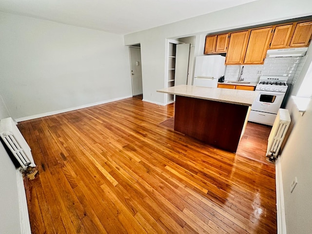 216-04 47th Ave Unit 1A, Bayside, NY 11361 - kitchen with white appliances, under cabinet range hood, light countertops, hardwood / wood-style flooring, and backsplash