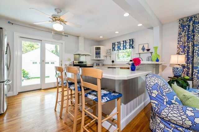 96 N Howells Point Rd, Bellport Village, NY 11713 - kitchen featuring wall chimney range hood, appliances with stainless steel finishes, a kitchen breakfast bar, plenty of natural light, and recessed lighting