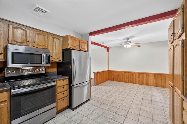 69 Crafts Rd, Carmel, NY 10512 - kitchen featuring stainless steel appliances, wainscoting, dark countertops, a ceiling fan, and wooden walls