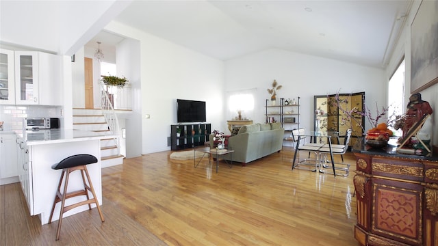 1651 201st St, Bayside, NY 11360 - living room featuring light wood-type flooring, vaulted ceiling, and stairs