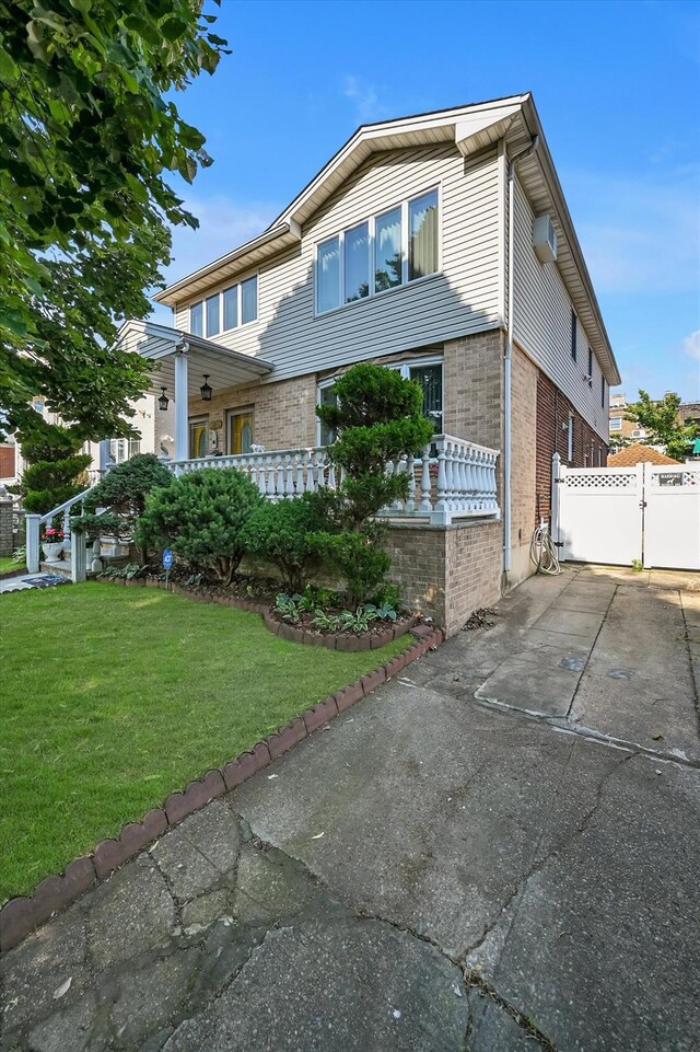 4539 192nd St, Flushing, NY 11358 - view of front of property with brick siding, a gate, and a wall mounted air conditioner