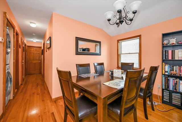 4539 192nd St, Flushing, NY 11358 - dining space featuring estacked washer and dryer, a chandelier, light wood finished floors, vaulted ceiling, and baseboards