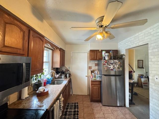 20817 15th Rd, Bayside, NY 11360 - kitchen featuring appliances with stainless steel finishes, a sink, ceiling fan, brown cabinetry, and brick wall