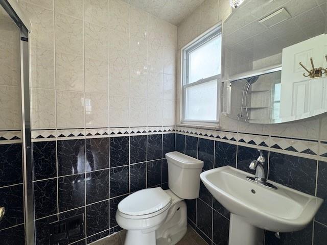 20817 15th Rd, Bayside, NY 11360 - bathroom featuring tile walls, toilet, a stall shower, and a sink