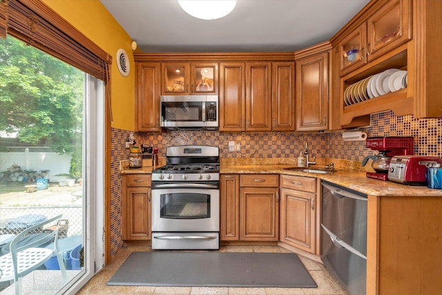 48-46 206th St Unit 2, Bayside, NY 11364 - kitchen featuring stainless steel appliances, a sink, tasteful backsplash, glass insert cabinets, and brown cabinets