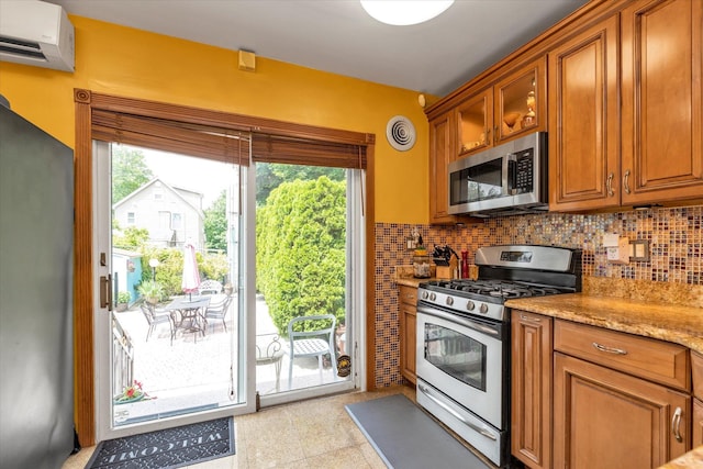48-46 206th St Unit 2, Bayside, NY 11364 - kitchen with stainless steel appliances, an AC wall unit, tasteful backsplash, brown cabinetry, and healthy amount of natural light