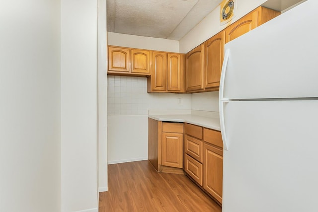 1321 Lafayette Ave, Bronx, NY 10474 - kitchen featuring freestanding refrigerator, light wood-style floors, light countertops, a textured ceiling, and brown cabinetry