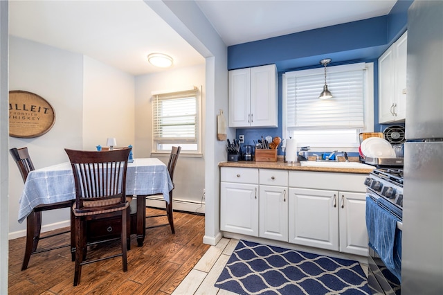721 E Walnut St, Long Beach, NY 11561 - kitchen featuring appliances with stainless steel finishes, a sink, light wood-style flooring, white cabinets, and light countertops