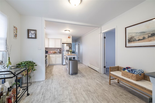 721 E Walnut St, Long Beach, NY 11561 - kitchen with freestanding refrigerator, white cabinets, baseboard heating, light wood-type flooring, and baseboards