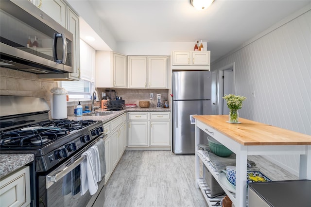 721 E Walnut St, Long Beach, NY 11561 - kitchen with appliances with stainless steel finishes, a sink, light wood-style flooring, tasteful backsplash, and light stone counters