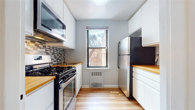 65-35 108th St Unit D7, Forest Hills, NY 11375 - kitchen featuring appliances with stainless steel finishes, radiator, butcher block countertops, and white cabinetry