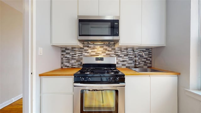 65-35 108th St Unit D7, Forest Hills, NY 11375 - kitchen featuring stainless steel appliances, a sink, white cabinetry, backsplash, and wooden counters