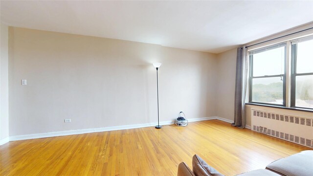 65-35 108th St Unit D7, Forest Hills, NY 11375 - empty room with radiator heating unit, light wood-type flooring, and baseboards
