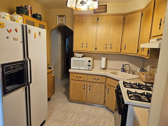 199-06 24th Rd, Whitestone, NY 11357 - kitchen with white appliances, under cabinet range hood, a sink, arched walkways, and a chandelier