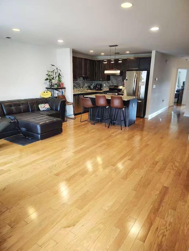 2-18A Constitution Pl Unit 173, College Point, NY 11356 - kitchen featuring open floor plan, under cabinet range hood, a kitchen breakfast bar, appliances with stainless steel finishes, and light wood finished floors