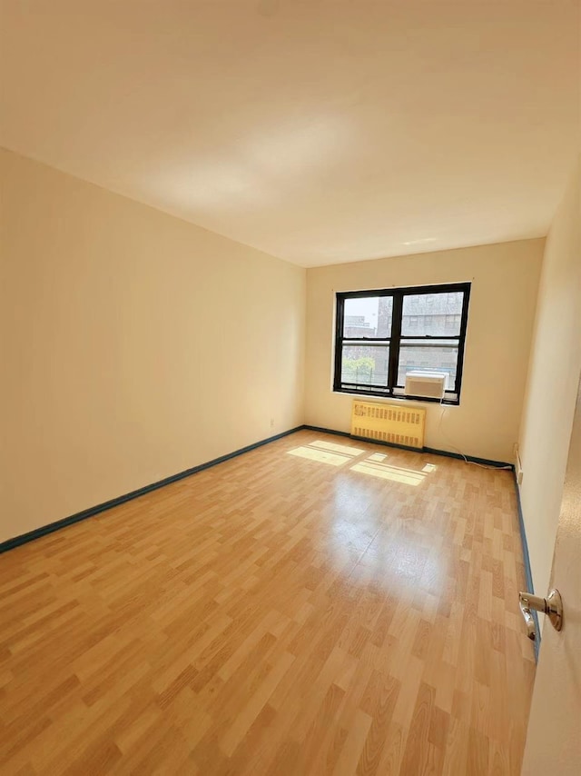 99-60 63rd Rd Unit 5W, Rego Park, NY 11374 - spare room featuring radiator heating unit, light wood-style flooring, and baseboards