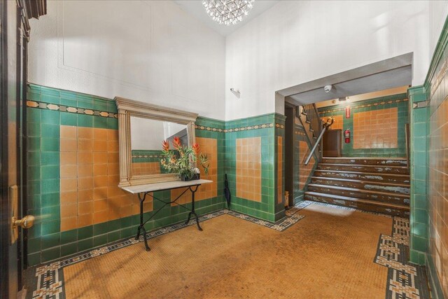 27 Locust Ave Unit 4N, New Rochelle, NY 10801 - bathroom featuring a high ceiling, a chandelier, tile walls, and wainscoting